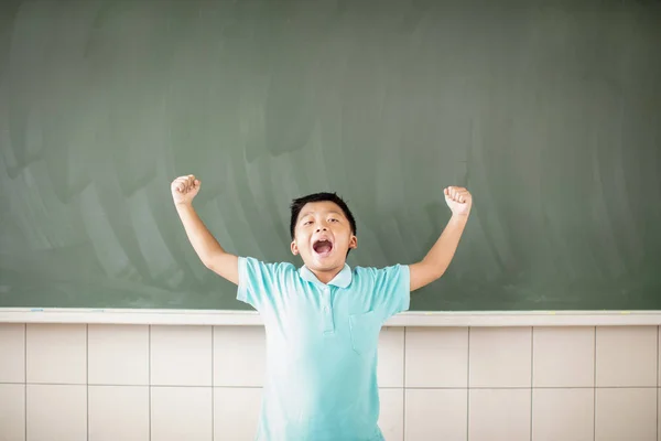 Happy school boy standing against chalkboard background Royalty Free Stock Images