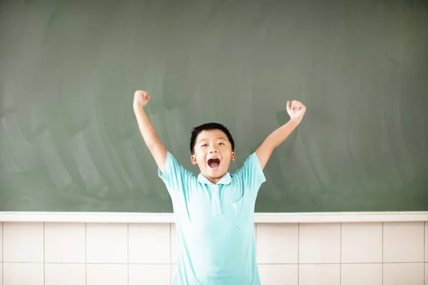 Happy school boy standing against chalkboard background Stock Photo