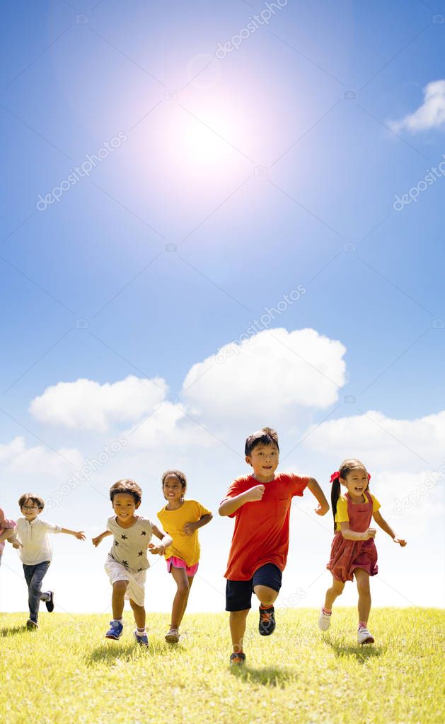 Multiethnic group of school children running on the grass
