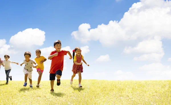 Multietnisk grupp av skolbarn som springer på gräset — Stockfoto