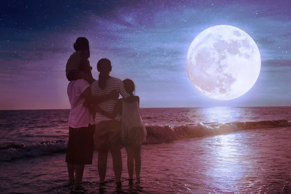 Rodzina stoi na plaży i patrzy na księżyc. Świętuj Mid-aut — Zdjęcie stockowe