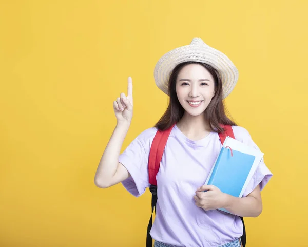 Молодая азиатская студентка держит книгу и указывает вверх — стоковое фото