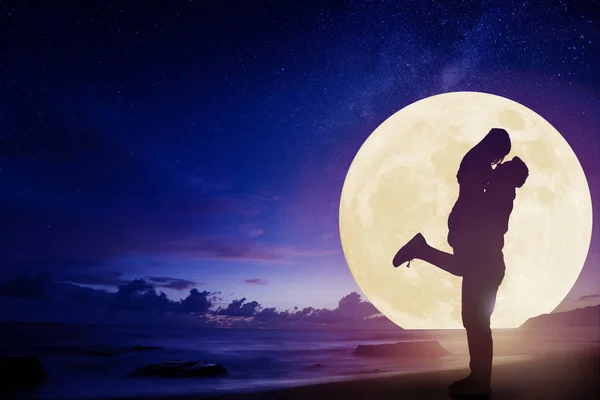 Junges Paar küsst sich am Strand und beobachtet den Mond. — Stockfoto