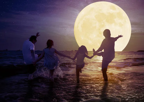 Rodinu, jak si hrají na pláži a sledují měsíc. Oslavovat Mid autu — Stock fotografie