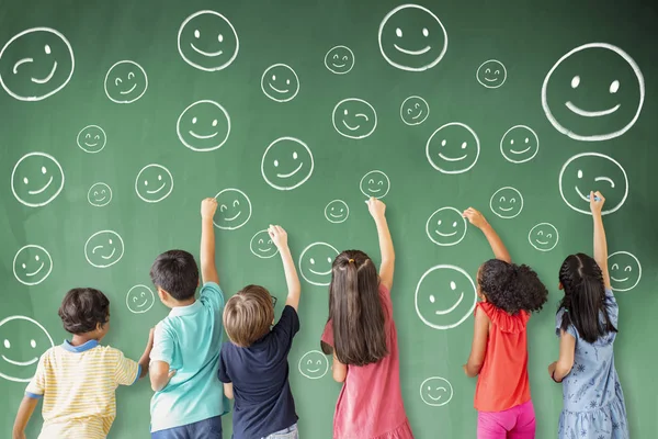 Niños de la escuela dibujando emoción icono de la cara en la pizarra — Foto de Stock