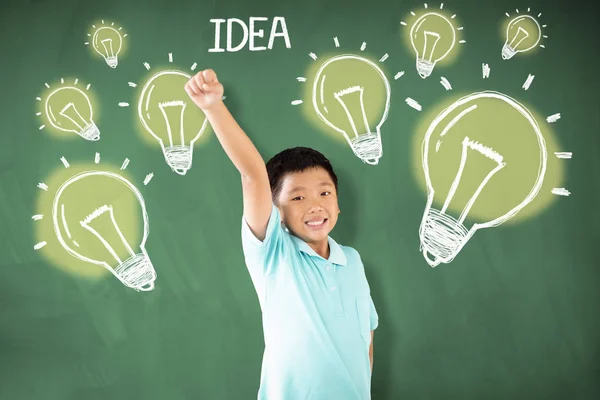 Gelukkig Aziatische jongen staande tegen schoolbord met idee Bulb concept — Stockfoto