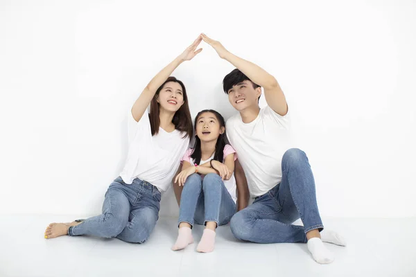 Glad ung familj sitter på golvet med hemmaplan — Stockfoto