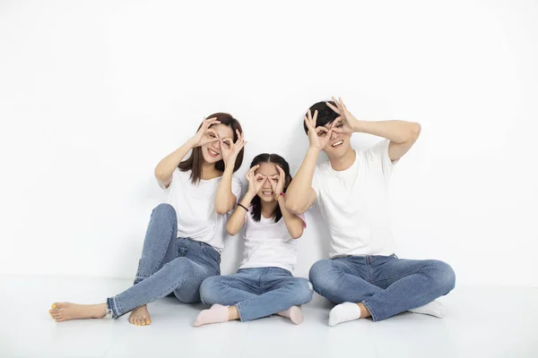 Gelukkig jong gezin zittend op de vloer met een uitziend gebaar — Stockfoto