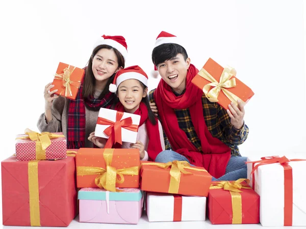 Familia feliz sentado en el suelo y mostrando regalo de Navidad — Foto de Stock