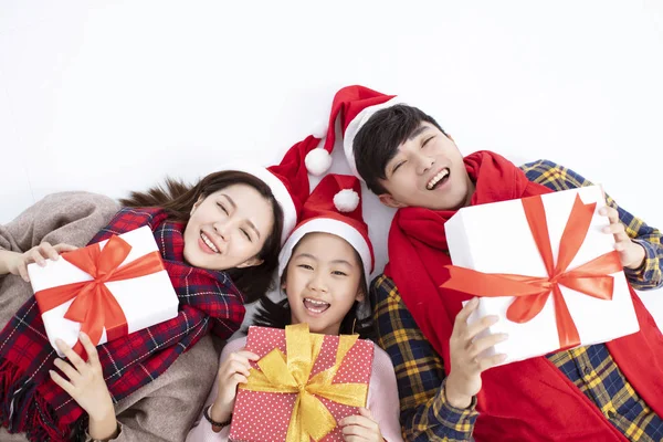 Ευτυχισμένη οικογένεια ξαπλωμένο στο πάτωμα και δείχνοντας χριστουγεννιάτικο δώρο — Φωτογραφία Αρχείου