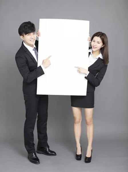 Молодой бизнесмен и женщина показывают чистый рекламный щит против гр. — стоковое фото