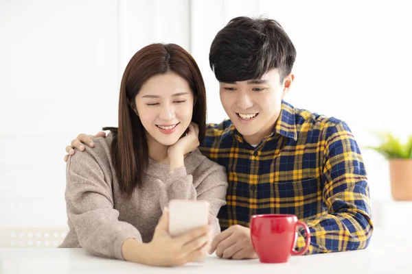 Joyeux jeune couple regardant le téléphone intelligent — Photo