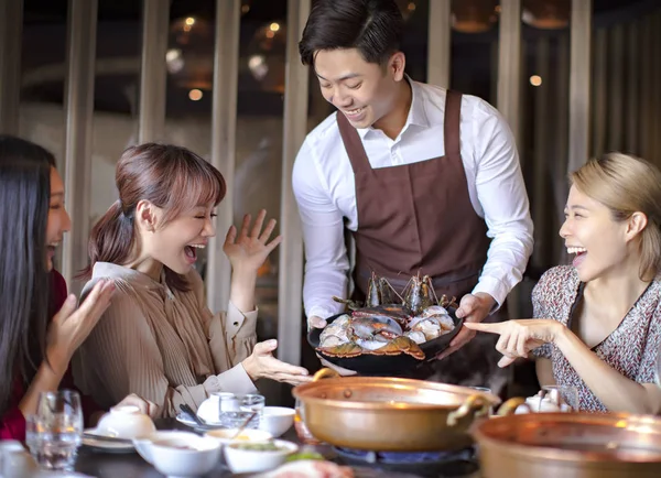 Felice cameriere portare frutti di mare e servire gruppo di amici in ri — Foto Stock