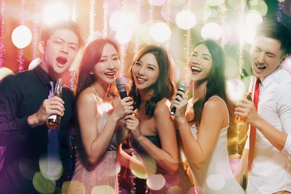 Grupo jovem segurando microfone e cantando no karaoke — Fotografia de Stock