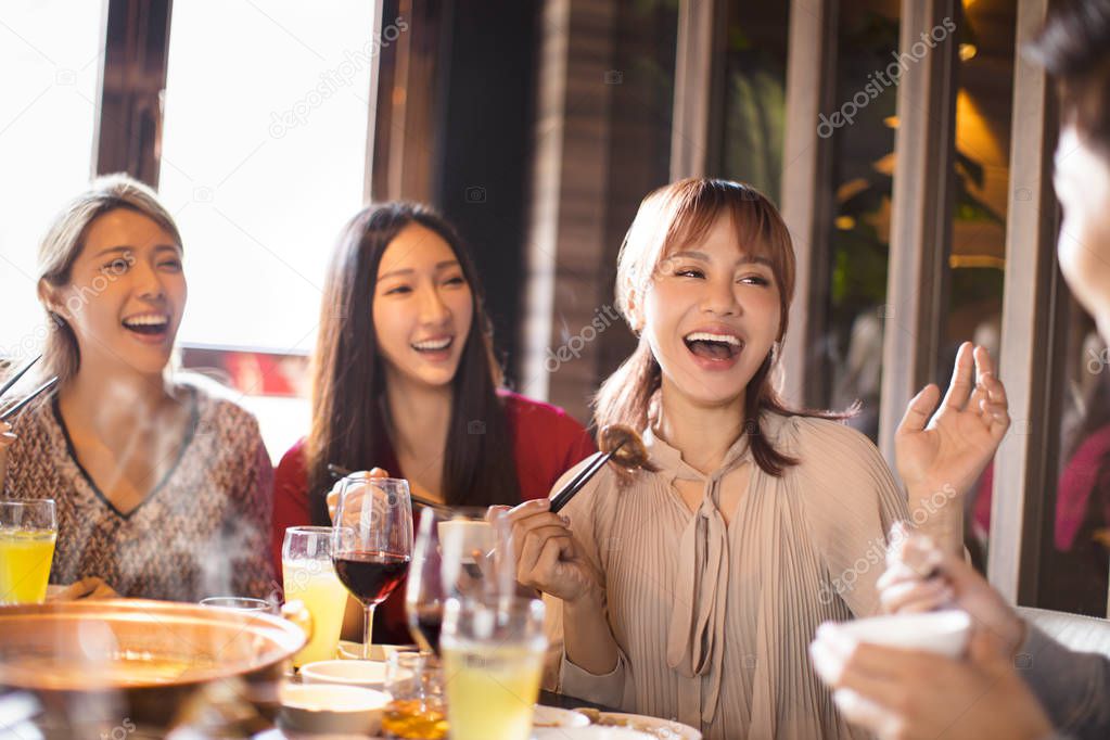 happy young friends enjoy dinner in hot pot restaurant 