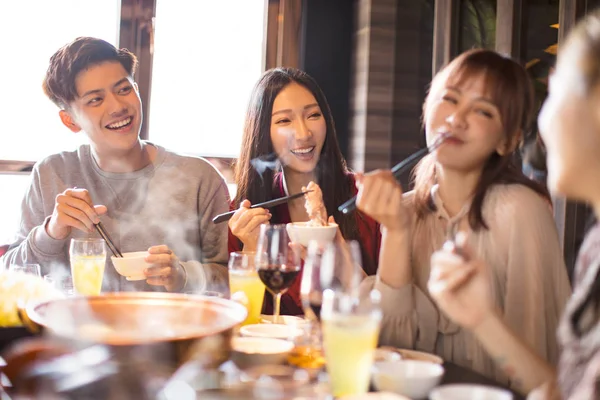Счастливые молодые друзья наслаждаются ужином в ресторане с горячей кастрюлей — стоковое фото