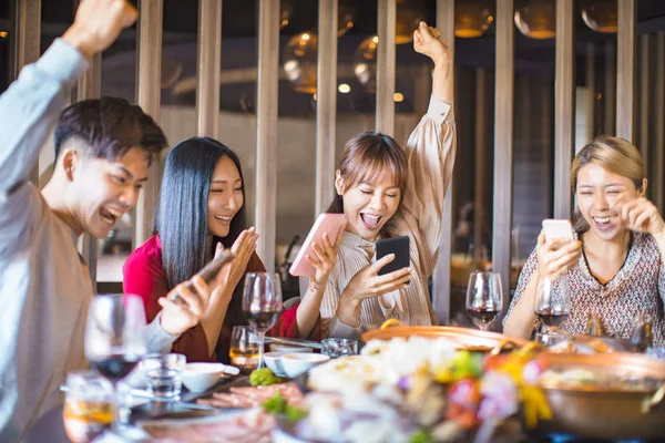 Gruppo di amici si divertono al ristorante e guardando sma — Foto Stock