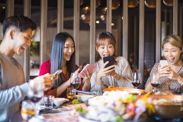 Grupo de amigos se divertindo no restaurante e olhando para sma — Fotografia de Stock