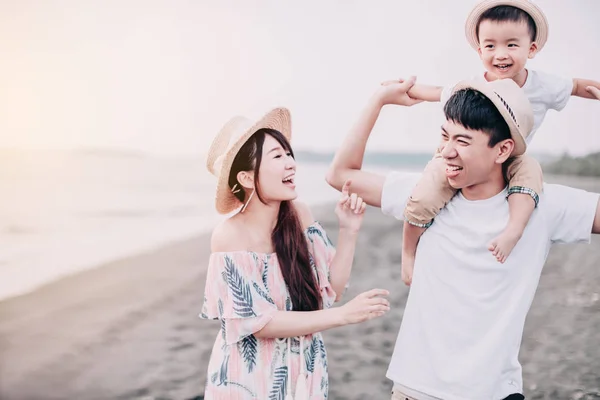 Lycklig asiatisk familj leker på stranden vid solnedgången — Stockfoto