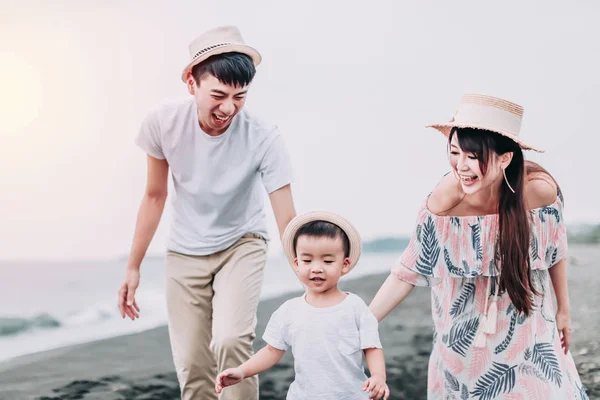 Happy asian family playing on the beach at sunset — ストック写真