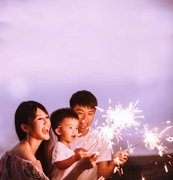 Felice famiglia che festeggia il nuovo anno con scintille sulla spiaggia — Foto Stock