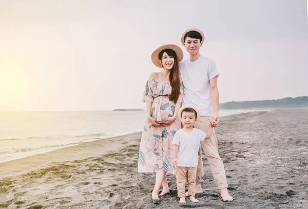 Lycklig asiatisk familj stående på stranden vid solnedgången — Stockfoto