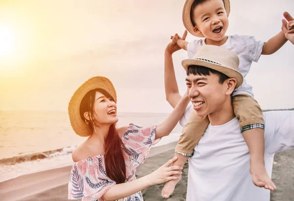 Gelukkig aziatische familie spelen op het strand bij zonsondergang — Stockfoto