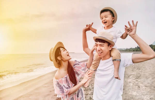 Счастливая семья, играющая на пляже на закате — стоковое фото