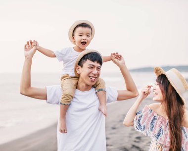 Mutlu Asyalı aile gün batımında sahilde oynuyor.