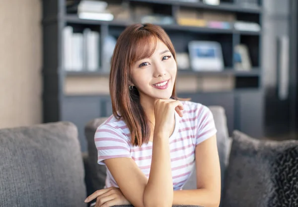 Sorrindo jovem mulher sentada no sofá — Fotografia de Stock