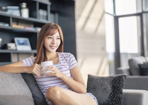 Mujer joven sonriente sentada en el sofá — Foto de Stock