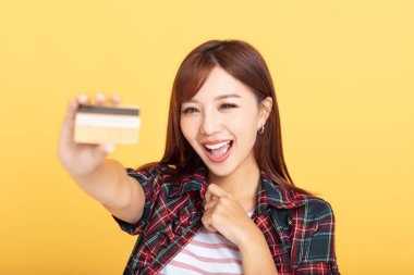 Kredi kartı gösteren mutlu ve çekici genç bir kadın.