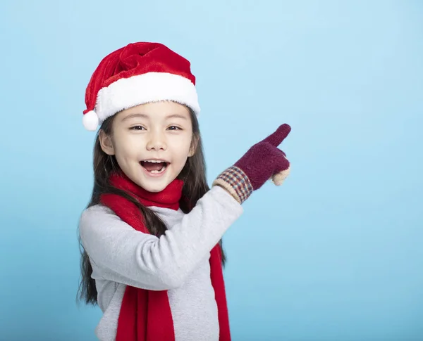 Glückliches kleines Mädchen in Weihnachtsmannmützen und auf etwas zeigend — Stockfoto