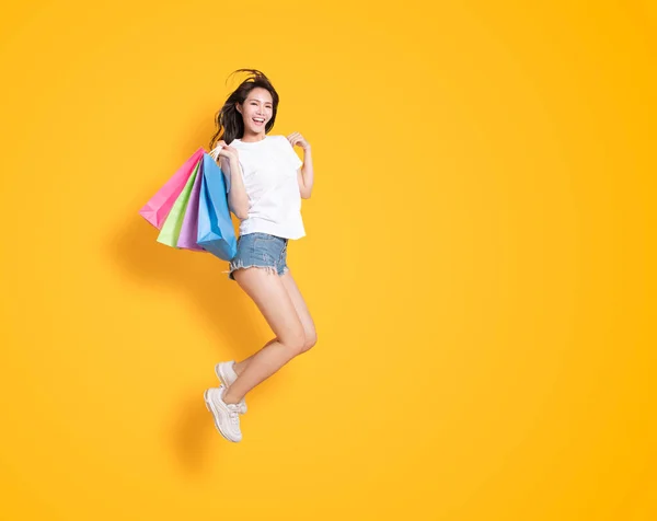 買い物袋を持って飛び跳ねる幸せな若い女性 — ストック写真