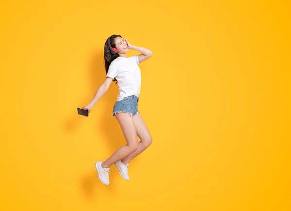 ヘッドフォンで音楽を聴きながら飛び跳ねる若い女性 — ストック写真