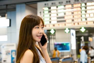  Tren istasyonunda genç bir kadın telefonda konuşuyor.