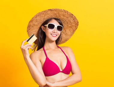 Bikini giyen ve kredi kartını gösteren genç ve güzel bir kadın.