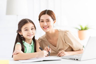 Anne çalışıyor ve kızına ev ödevi yaptırıyor.