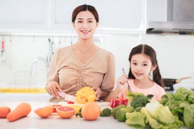 Mutlu anne ve kız sebze ve meyve hazırlıyor.