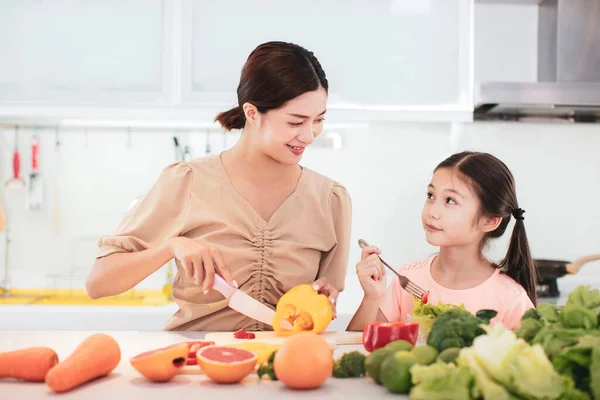 野菜や果物を食べる幸せな母と子の娘 — ストック写真