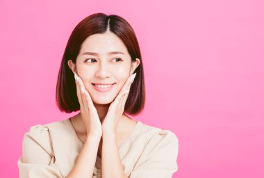 Asyalı genç güzellik yanaklarını tutuyor ve yana bakıyor.