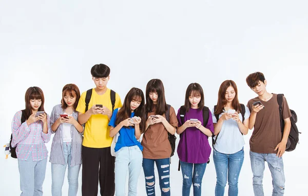 Młoda Grupa Studentów Oglądająca Telefon Komórkowy Stojąca Razem — Zdjęcie stockowe