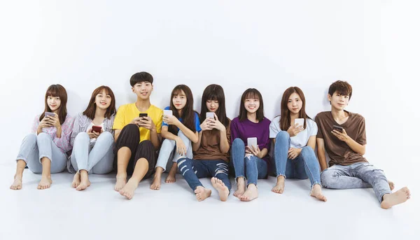 young group using smartphones and  sitting on the floor