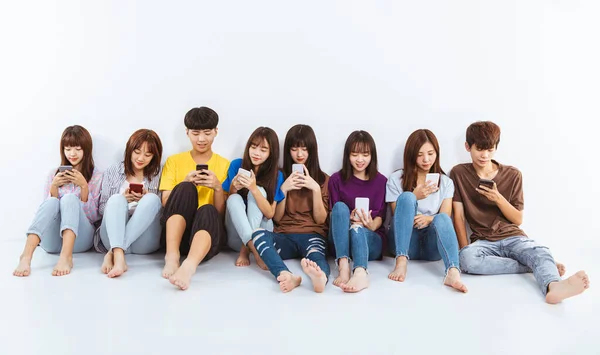 使用智能手机坐在地板上的年轻群体 — 图库照片