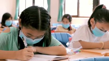 Öğrenciler sınıfta maske takıp ders çalışıyor.