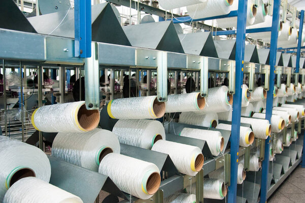 Textile industry - yarn spools on spinning machine in a textile factory