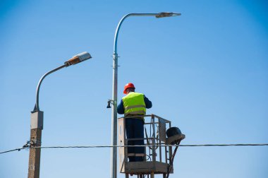 Elektrikçiler elektrik direğindeki elektrik hattını tamir ediyorlar.