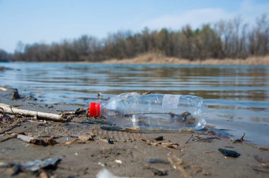 Nehrin kıyısında plastik şişeler ve çöp atıkları.