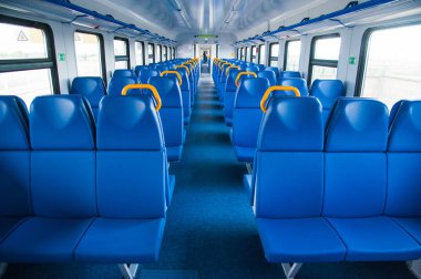Mavi koltuklu bir tren kulübesinin içinde ve pencereden içeri güneş ışığı giriyor.