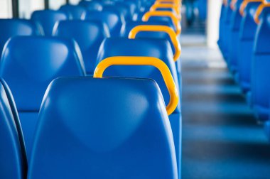 Mavi koltuklu bir tren kulübesinin içinde ve pencereden içeri güneş ışığı giriyor.